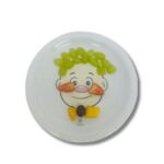 Prato de cerâmica branco, quadrado, com um desenho de um rosto de menino sorrindo, decorado com brócolis como cabelo e outros alimentos para formar um rosto divertido.