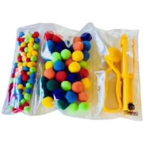 Kit Pinça e Pompons da Materiais para Brincar, mostrando uma pinça de plástico sendo usada para pegar um pompom colorido, com outros pompons de diferentes tamanhos e cores ao lado.