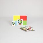 Jogo Balão Colorido da Materiais para Brincar, mostrando uma placa de madeira com um balão vazado posicionado sobre uma superfície colorida, formando uma combinação de cores.