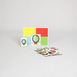 Jogo Balão Colorido da Materiais para Brincar, mostrando uma placa de madeira com um balão vazado posicionado sobre uma superfície colorida, formando uma combinação de cores.