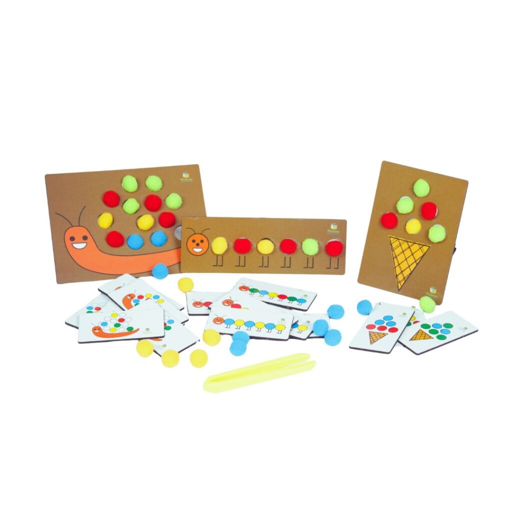 Jogo Centopeia, Caracol e Sorvete da Materiais Para Brincar, mostrando uma das placas de MDF com alguns pompons coloridos já inseridos nos furos, e uma criança usando a pinça para colocar outro pompom.