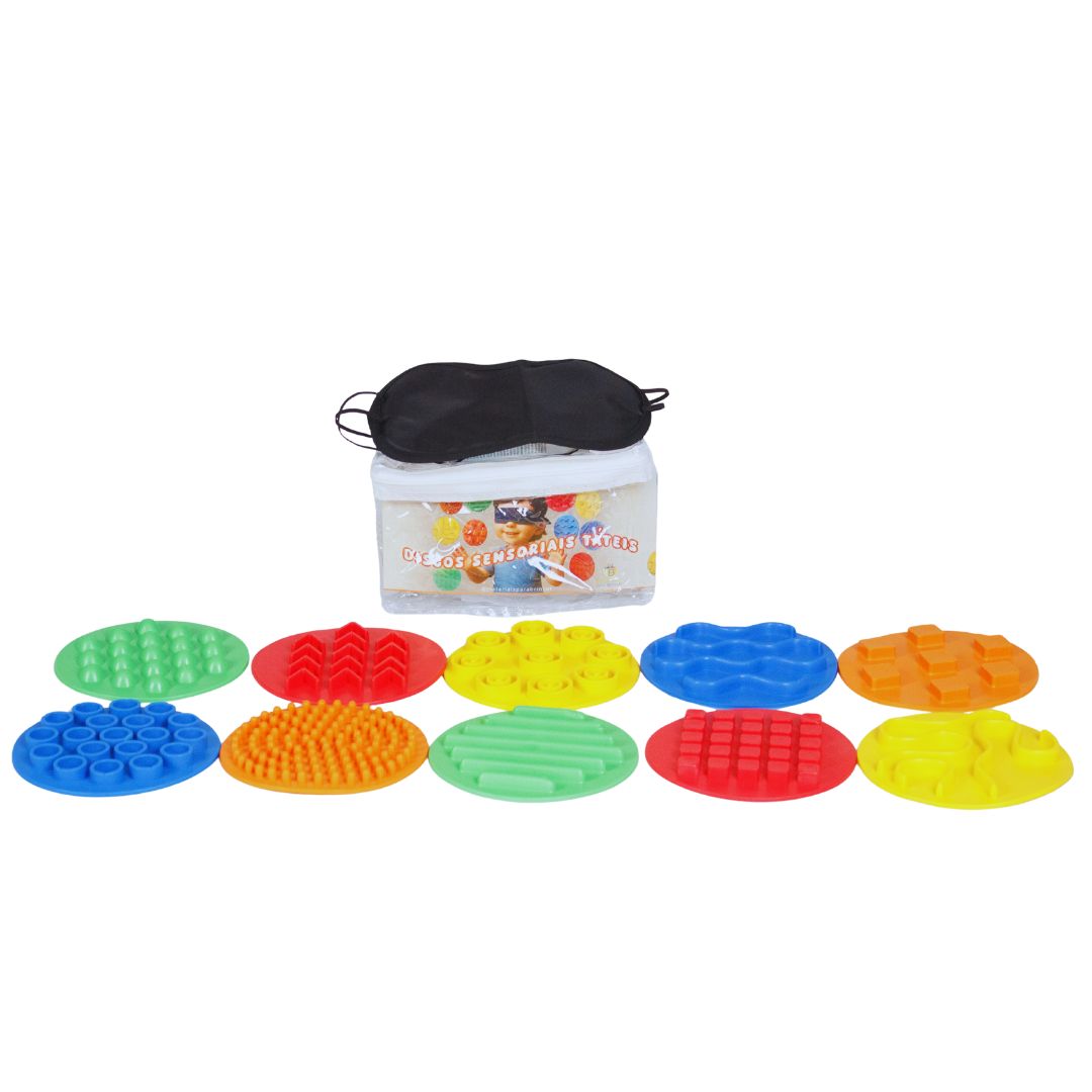 Discos sensoriais táteis 3 Kit de 10 discos sensoriais táteis coloridos sobre um fundo claro. Discos têm texturas variadas e estão organizados em duas fileiras, junto a um tapa-olho preto.
