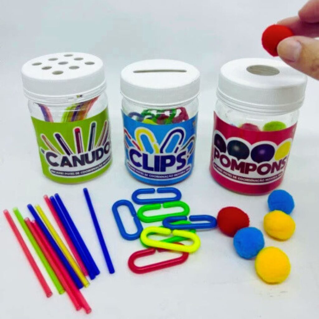 Kit de Encaixe da Materiais para Brincar, com 3 potes coloridos e vários pompons, canudos e clips espalhados.