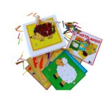O jogo Martelando da Materiais Para Brincar, mostrando uma mão de criança usando um martelo de madeira para inserir um preguinho colorido em uma das fichas perfuradas, que está sobre uma placa de isopor.