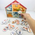 Brinquedo Minha Casa da Materiais para Brincar, mostrando uma casinha em MDF com fichas de móveis e pessoas sendo encaixadas.