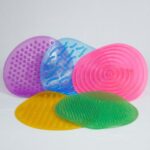 Kit Tapete Sensorial da Materiais Para Brincar, mostrando os 5 tapetes coloridos e texturizados (com pontinhos, ondas, etc.) dispostos lado a lado no chão. Uma criança pode estar descalça sobre um dos tapetes.