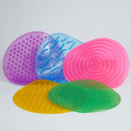 Kit Tapete Sensorial da Materiais Para Brincar, mostrando os 5 tapetes coloridos e texturizados (com pontinhos, ondas, etc.) dispostos lado a lado no chão. Uma criança pode estar descalça sobre um dos tapetes.